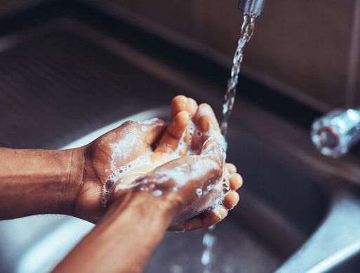 Someone washing their hands under a tap with soap
