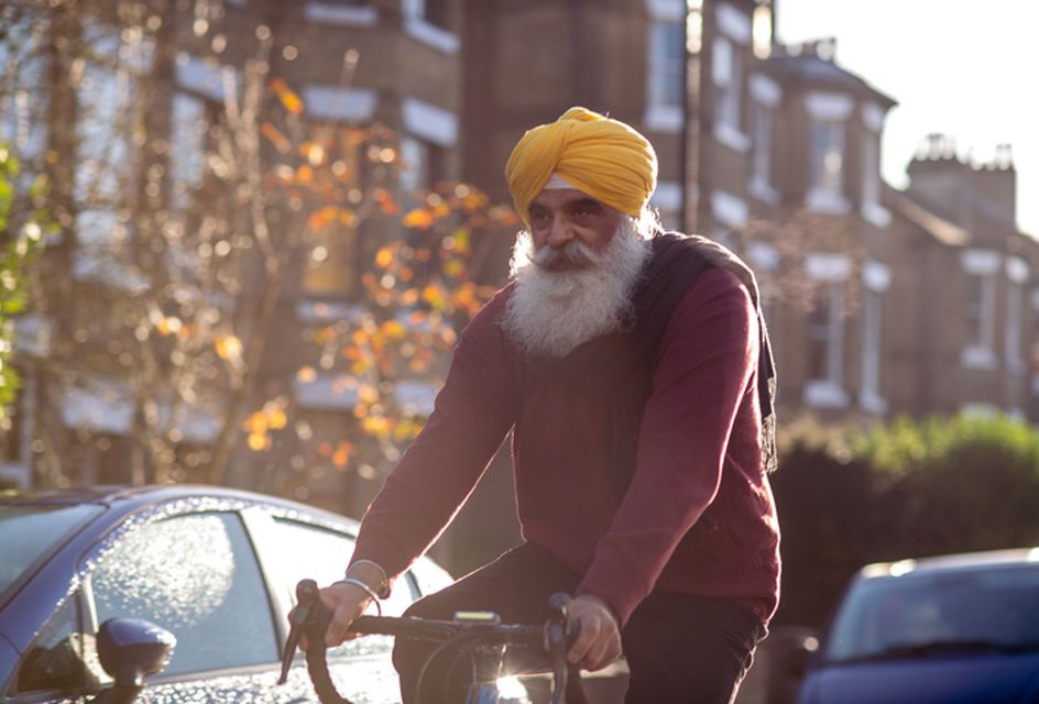 An older sikh man riding a bicycle