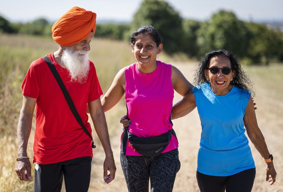 A group of two women and a man take a walk in the park.