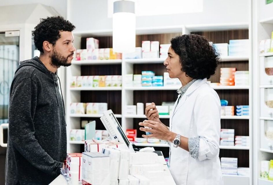 A female pharmacist talks to a male customer in a pharmacy.