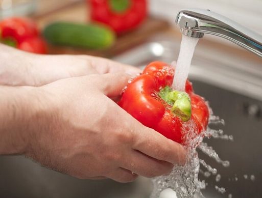 Someone washing a red pepper under a running tap