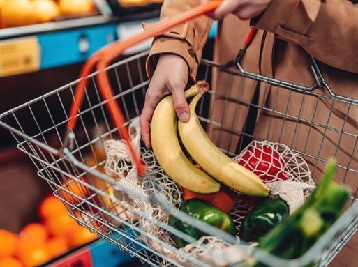A basket of food in a supermarket, containing bananas, peppers and courgettes