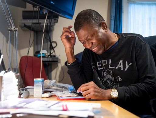 An elderly black mine smiles as he looks at his phone