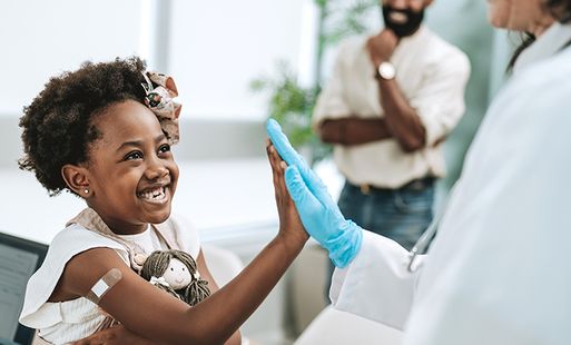 Smiling young girl high-fiving a medical worker after receiving a vaccine