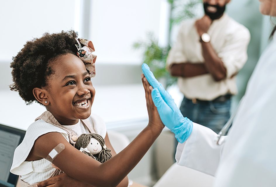 Smiling young girl high-fiving a medical worker after receiving a vaccine
