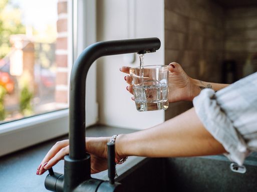 Someone filling up a glass of water from a kitchen tap.