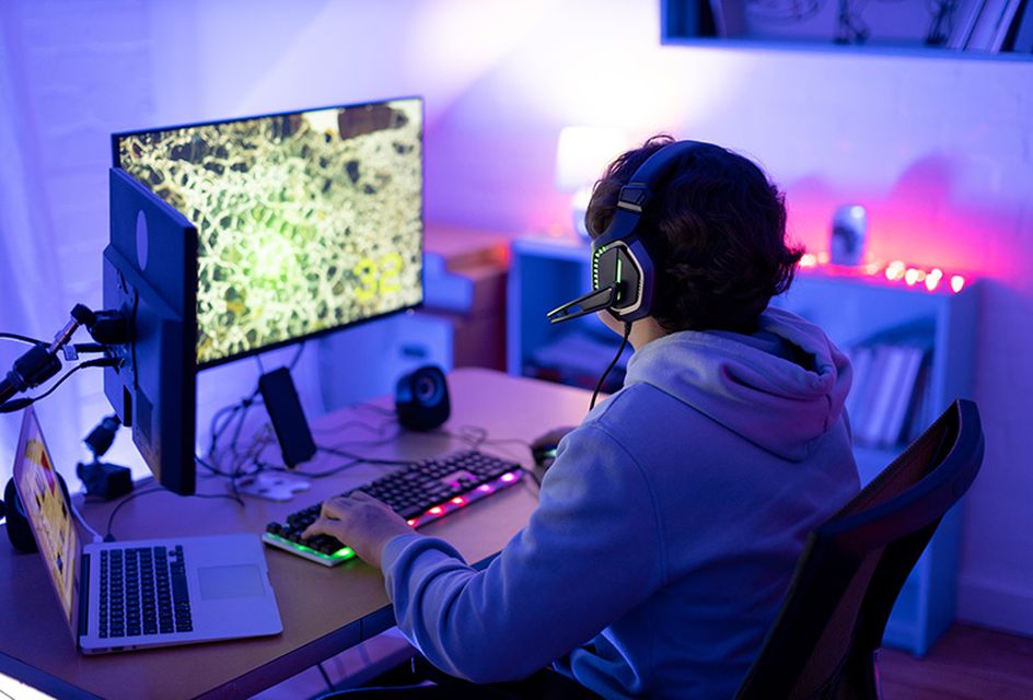 A teenager with headphones on plays videogames in his bedroom