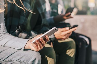 A row of teenagers holding mobile phones