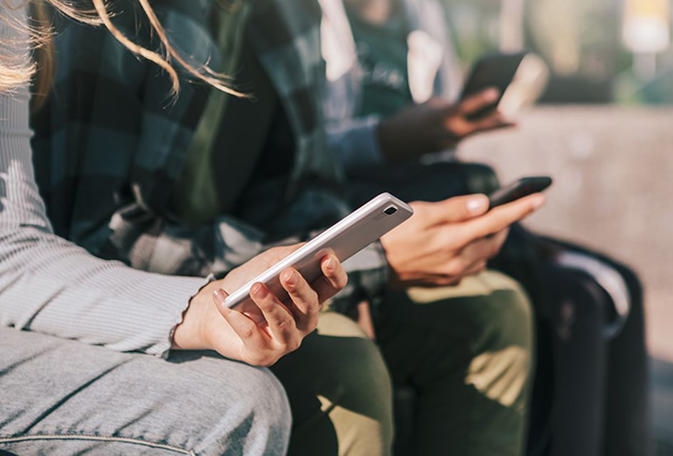 A row of teenagers holding mobile phones