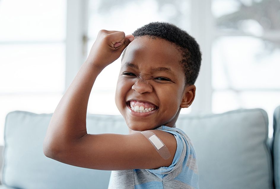 Young boy with plaster on his arm cheering with happiness after getting a vaccination