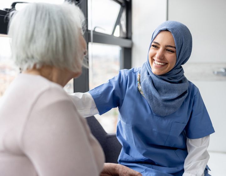 Healcare worker wearing a hijab laughing with an older woman patient, representation of the work of RSPH membership