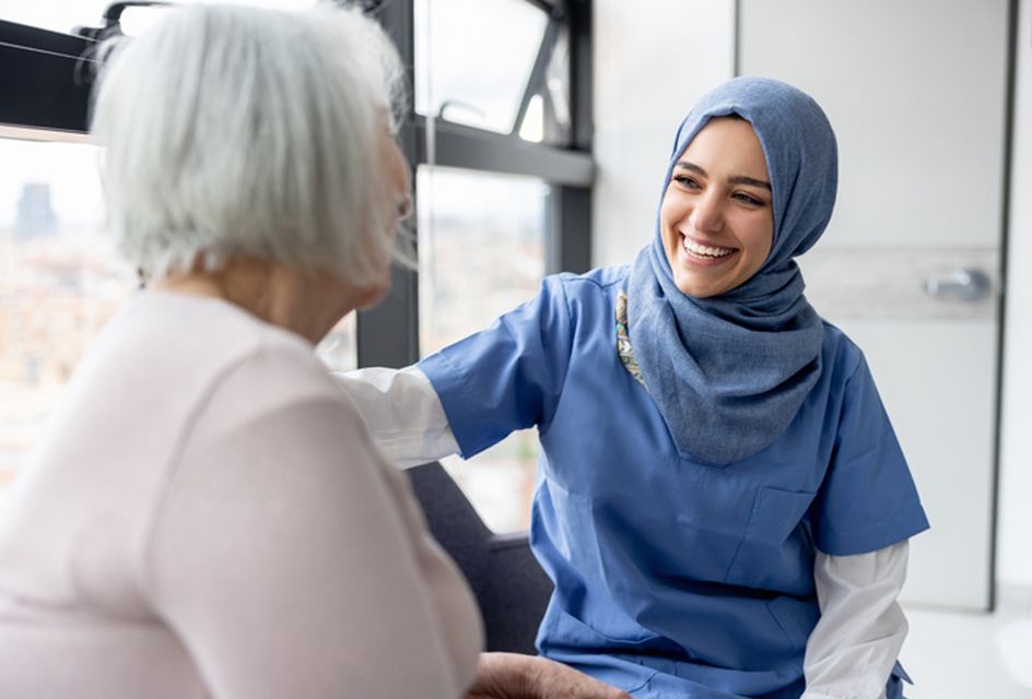 Healcare worker wearing a hijab laughing with an older woman patient, representation of the work of RSPH membership