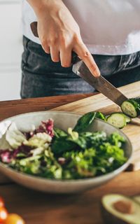 Someone chopping a cucumber on a chopping board in a kitchen
