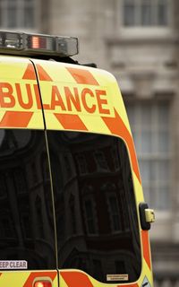 The back of an ambulance with yellow and red stripes and text that reads "ambulance".
