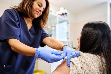 A nurse providing a vaccine to a female patient