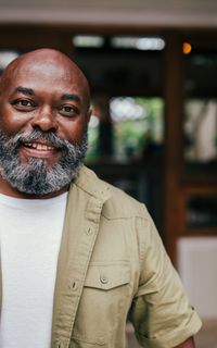 An older black man with a grey beard smiles at the camera.
