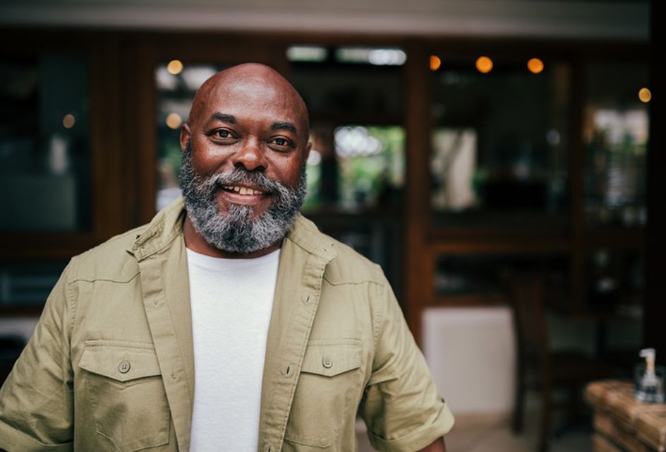 An older black man with a grey beard smiles at the camera.