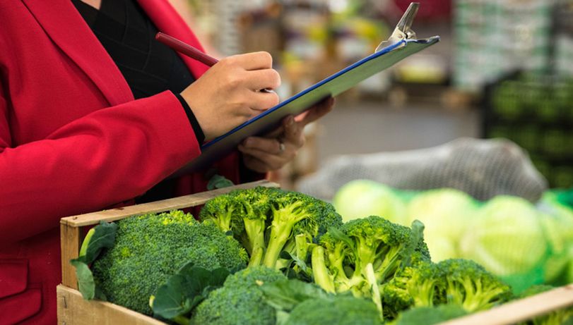 A food safety specialist inspects a crate of brocolli.