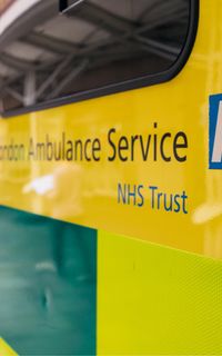 A close-up of an ambulance which has text reading "London Ambulance Service NHS Trust" and the NHS logo.