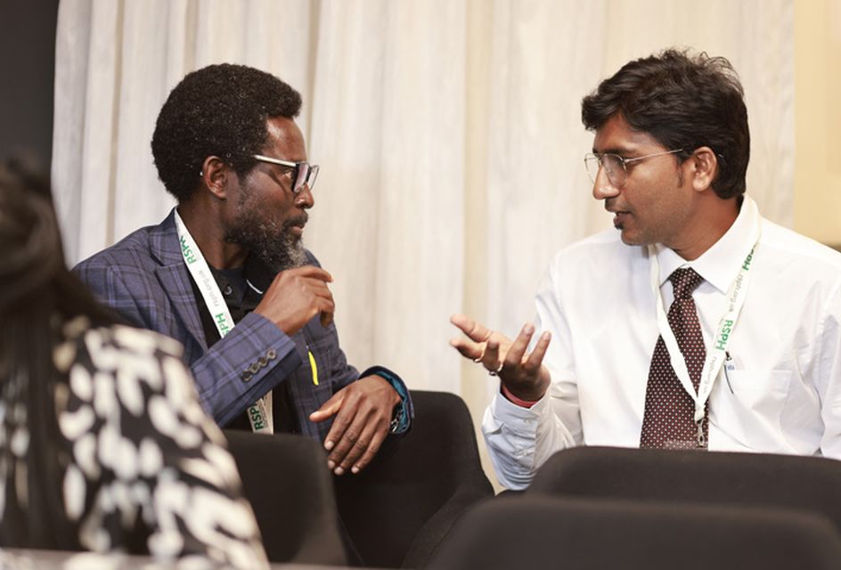 Two men talk at an RSPH event. They are both wearing RSPH lanyards.