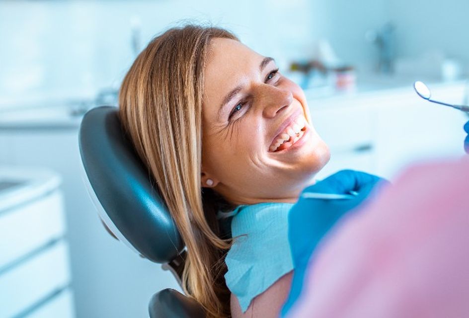 A woman smiles while sitting in a dentist chair