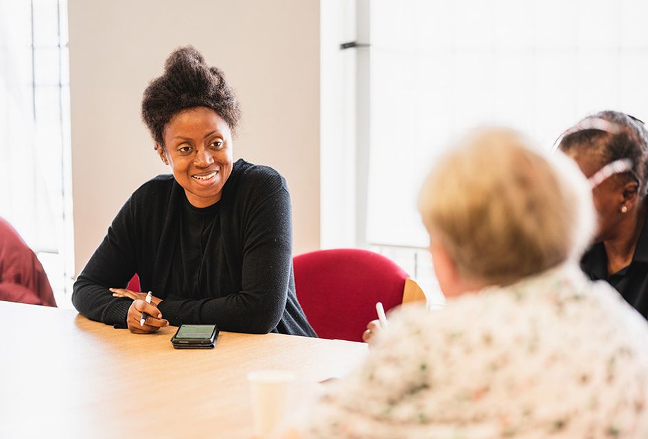 A black woman speaks to an older white woman.