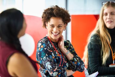 A woman in a professional setting is talking with her colleagues.